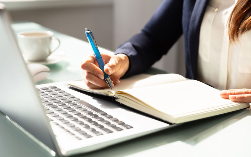 Perempuan menulis di depan laptop