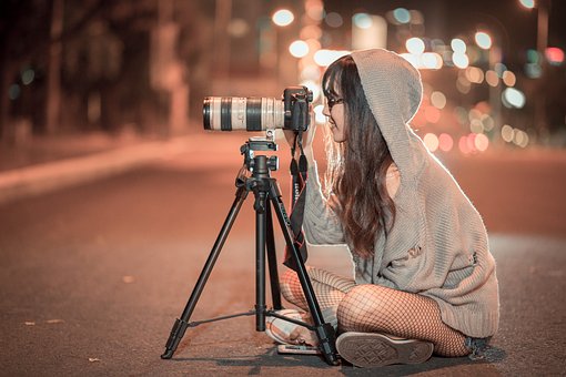 Fotografer perempuan duduk di tengah jalan